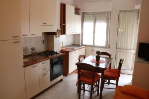 eine Küche mit einem Tisch und Stühlen sowie eine Küche mit weißen Schränken in der Unterkunft Maremma Holidays - Cimarosa Apartment in Follonica