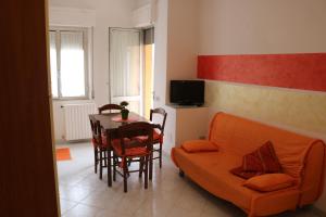 ein Wohnzimmer mit einem orangenen Sofa und einem Tisch in der Unterkunft Maremma Holidays - Cimarosa Apartment in Follonica