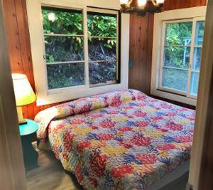 a bedroom with a bed and two windows at Aeolian Ranch in Kailua-Kona