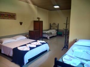 a bedroom with two beds and a cross on the wall at Casa de Noca Paquetá in Rio de Janeiro