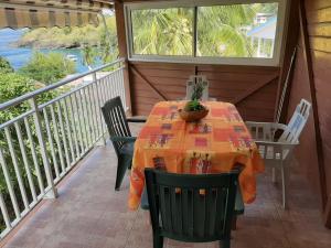 una mesa y sillas en el porche de una casa en Les Hibiscus, en LʼAnse Noire
