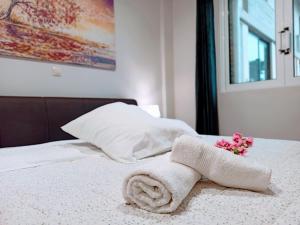 een witte handdoek op een bed met bloemen erop bij Central Square Apartment 1 in Pýrgos
