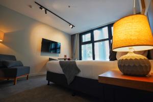 a bedroom with a bed with a lamp and a chair at City Edge South Melbourne Apartment Hotel in Melbourne