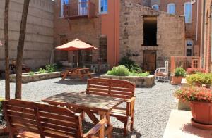 eine Terrasse mit 2 Bänken, einem Tisch und einem Sonnenschirm in der Unterkunft Windsor Hotel & Restaurant in Del Norte