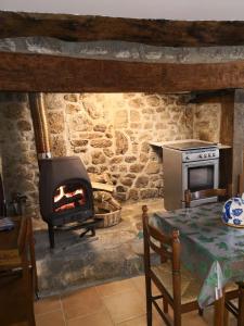 - un salon avec une cuisinière, une table et une cheminée dans l'établissement ESCALE NATURE, à Saint-Angel