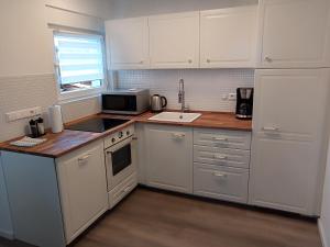 a kitchen with white cabinets and a sink and a microwave at Ferienwohnung Waldvogel in Immenstaad am Bodensee