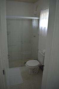 a white bathroom with a toilet and a shower at Suites Vida Mansa in Maresias