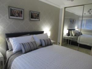 a bedroom with a large white bed with a mirror at Levenview Holiday Apartment Loch Lom in Balloch