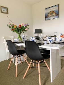 een witte tafel met stoelen en een vaas met bloemen bij Harlingen Garden Apartment in Midlum