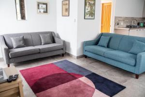 a living room with two couches and a rug at Swansea Valley Holiday Cottages in Cilybebyll