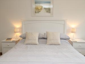 Un dormitorio con una cama blanca con dos lámparas. en Little Forge, en West Lulworth 21 fotos más