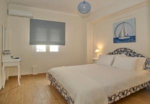 1 dormitorio con cama, mesa y ventana en The Bluehouse - Spacious top floor flat with parking, by Mon Repos beach en Corfú