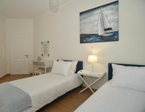 a bedroom with two beds and a table with a sail on the wall at The Bluehouse - Spacious top floor flat with parking, by Mon Repos beach in Corfu Town