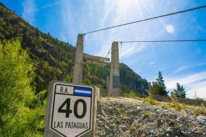 un panneau sur une route avec un pont en arrière-plan dans l'établissement Hostería de Montaña Las Pataguas, à El Hoyo