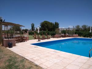 Una piscina en un patio con mesas y sillas. en Hotel Cañon de Talampaya, en Villa Unión 92 fotos más