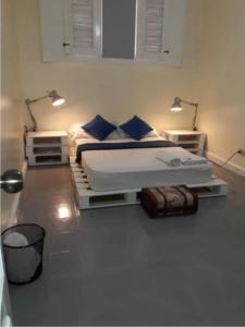 a bedroom with a bed with blue pillows and two lights at Recycled house in Santo Domingo