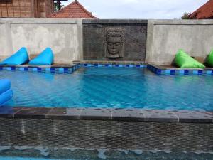 una piscina con una estatua en el medio en Devadav Hostel (Bunk Bed) Nusa Lembongan en Nusa Lembongan