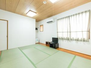 une chambre vide avec des murs blancs et une fenêtre dans l'établissement Hotel Isesaki East, à Isesaki