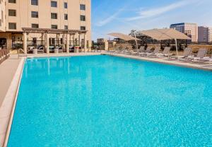 オースティンにあるHoliday Inn Express Hotel & Suites Austin Downtown - University by IHGの青い大型スイミングプール(椅子付)と建物
