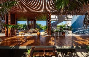 una sala de estar con una terraza de madera con palmeras en Beachfront Villa in the middle of jungle!, en Tulum