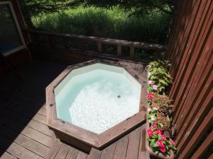 eine Holzbadewanne auf einer Terrasse mit Blumen in der Unterkunft Guesthouse Curry Village in Hokuto