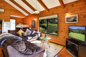 sala de estar con sofás y TV de pantalla plana. en Siver Cabin en Kangaroo Valley