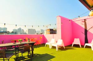 ソウルにあるOYO Hostel Dongdaemun1のピンクの壁のパティオ(テーブル、椅子付)