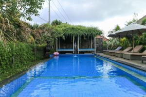 a swimming pool in a garden with an umbrella at Koji Garden Huts - CHSE Certified in Nusa Lembongan