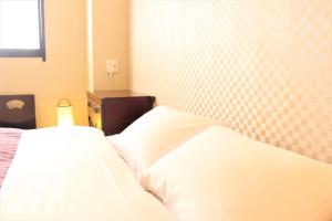 a bedroom with a white bed with a checkered headboard at K's House Tokyo Oasis - Asakusa Downtown in Tokyo