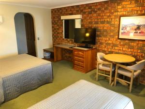 Habitación de hotel con cama, mesa y TV en Victoriana Motor Inn en Ballarat