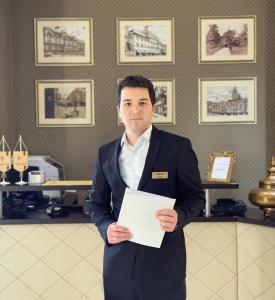 a man in a suit holding a piece of paper at Hotel Banja Luka in Banja Luka