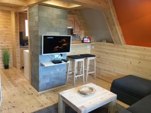 ein Wohnzimmer mit einem TV an einer Steinmauer in der Unterkunft Wooden Apartman Prémium Jacuzzival in Alsóörs