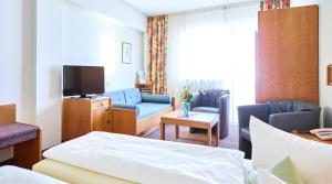 ローテンブルク・オプ・デア・タウバーにあるホテル メリアン ローテンブルクのベッド、ソファ、テレビが備わるホテルルームです。