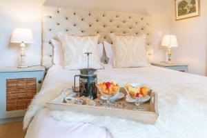 a bed with a tray with fruit on it at Aloe Cottage at Ibis House in Cape Town +11 photos