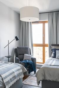 a bedroom with a bed and a chair and a window at Sea view apartment in Gdańsk