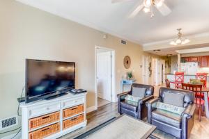 a living room with a flat screen tv and two chairs at Crystal Tower Condominiums in Gulf Shores