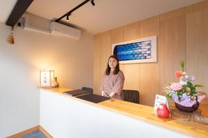 a woman standing at a counter in a room at 京一軒町家 染 SEN 七条花畑 Shichijo-Hanabatake in Kyoto