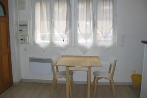una mesa de madera y sillas en una habitación con ventanas en Petit studio à BORDEAUX CHARTRONS / JARDIN PUBLIC (6), en Burdeos