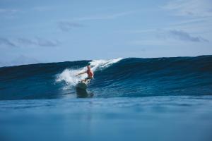 a man riding a wave on a surfboard in the ocean at Soneva Jani in Dhigurah