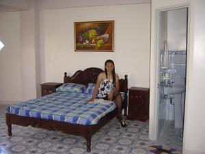 a woman sitting on a bed in a room at Seasun Beach Resort & Hotel in Santa Cruz