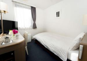 a bedroom with a bed and a desk with a computer at Grand Park Hotel Panex Tokyo in Tokyo