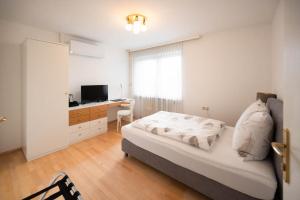 una camera da letto con un letto, una scrivania e una televisione di Aparthome L.I.N.Z. a Bergham
