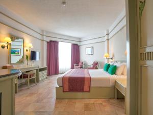 a hotel room with a large bed and a desk at Cholchan Pattaya Beach Resort - SHA Extra Plus in Naklua 