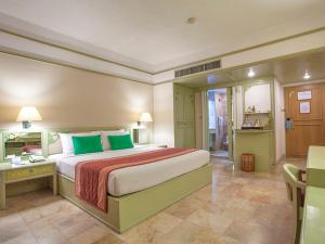 - une grande chambre avec un grand lit et des oreillers verts dans l'établissement Cholchan Pattaya Beach Resort - SHA Extra Plus, à Naklua