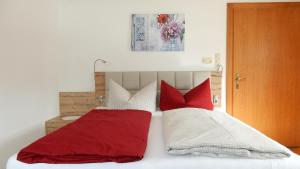 a bedroom with a bed with red and white pillows at Ferienwohnung Dreer in Hofen