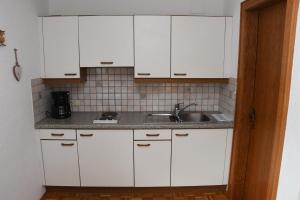 a kitchen with white cabinets and a sink at Ferienwohnung Dreer in Hofen