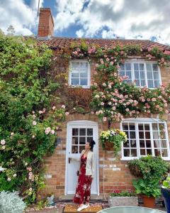 una mujer parada en la puerta de una casa con rosas en The Cottage Hotel, en Nottingham