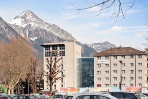 a large building with a mountain in the background at Campanile Martigny in Martigny-Ville