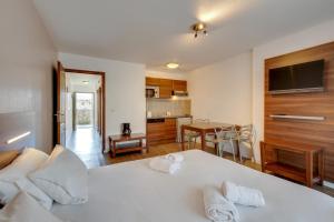 Cet appartement comprend une chambre avec un lit blanc et une cuisine. dans l'établissement Résidence Azurea, à Aix-les-Bains