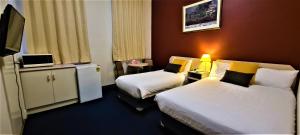 um quarto de hotel com duas camas e uma televisão em Brunswick Tower Hotel em Melbourne